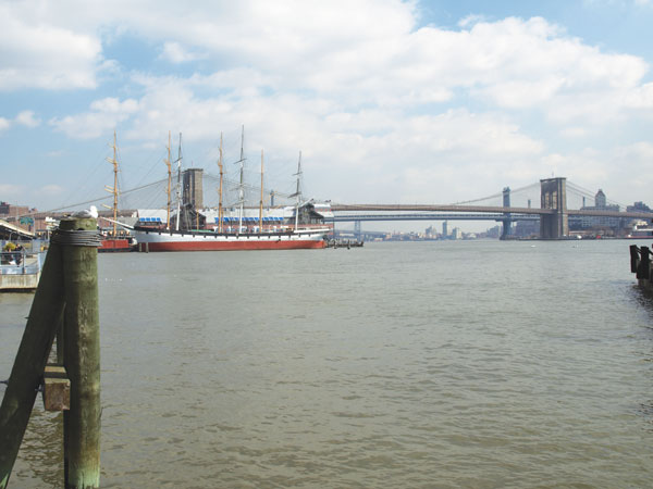Downtown Express file photo  The South Street Seaport Museum’s historic vessels in front of “Two Bridges, ” the Brooklyn and Manhattan. The photo was taken prior to the demolition of Pier 17, which is currently being rebuilt with a new design.