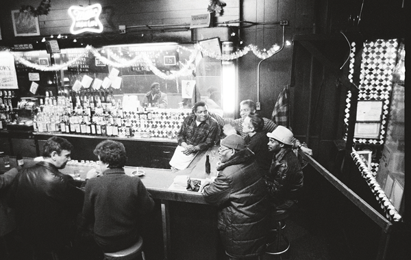 Behind the bar, to serve and preserve 7 Jersey, bartending, with some of the regulars (1980). Photo by Sheldon Nadelman