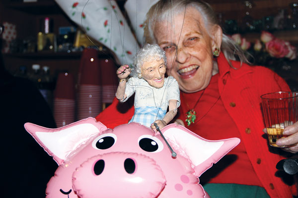 Clockwise from above left, Doris Diether laughed as the “Little Doris” marionette rode a blow-up pig; a creative custom cake featured the park arch, Diether, “Little Doris” and the pig; marionette master Ricky Syers was up to his usual tricks; Harvey Osgood opened his house for the party.   Photos by Tequila Minsky