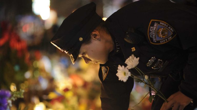 New York City police officers visit the makeshift memorial for slain NYPD officers Wenjian Liu and Rafael Ramos at the intersection of Tompkins Avenue and Myrtle Avenue in Brooklyn on Tuesday, December 23, 2014.