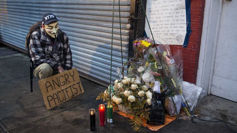 A protester kneels Wednesday, Dec. 3, 2014, near the spot where Eric Garner died in July while he was being put into police custody. 