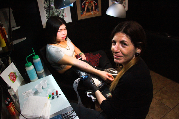 Linda Wulkan, right, at work on a customer’s tattoo on St. Mark’s Place.  PHOTO BY CLAYTON PATTERSON
