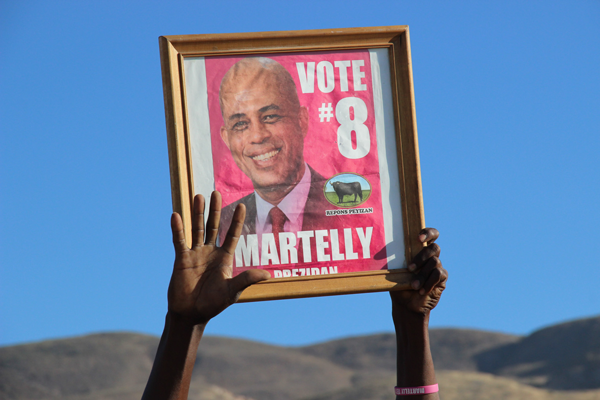 Outside the commemoration ceremony for Haitian earthquake victims, a pro-Martelly demonstrator held up a framed election poster. Others protested against the president.   Photo by TEQUILA MINSKY