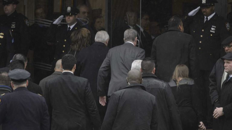 Two city cops salute as Police Commissioner William J. Bratton, Mayor Bill de Blasio, and First Deputy Commissioner Benjamin Tucker, arrive at the wake of Det. Wenjian Liu at Aievoli Funeral Home in Brooklyn on Saturday, Jan. 3, 2015. 