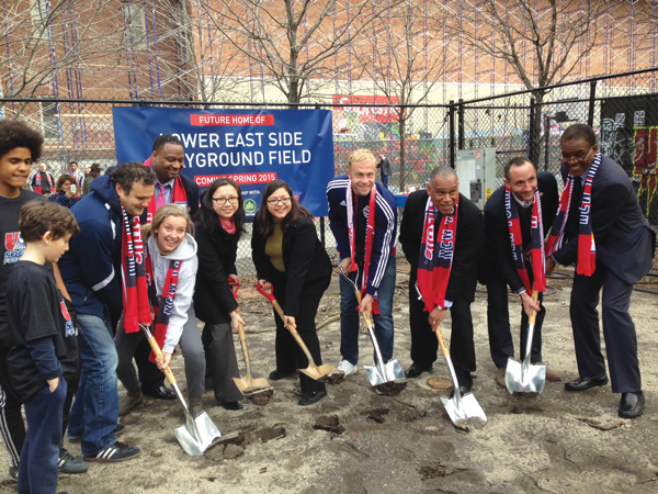 At groundbreaking for new E. 11th St. field, from left, Mark Federman, principal, East Side Community High School; Darryl Rattray, assistant commissioner of Beacon, Cornerstone and Service Learning; Monique Flores, program director, University Settlement’s Beacon and Cornerstone afterschool programs; C.B. 3 Chairperson Gigi Li; Councilmember Rosie Mendez; Red Bulls player Mike Grella; Parks Commissioner Mitchell Silver; Red Bulls General Manager Marc de Grandpre; and Ed Foster-Simeon, president and C.E.O., U.S. Soccer Foundation.