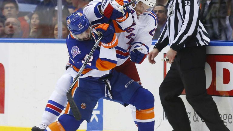 Cal Clutterbuck of the New York Islanders battles for the puck in the second period against Dominic Moore of the New York Rangers at Nassau Coliseum on Tuesday, March 10, 2015.