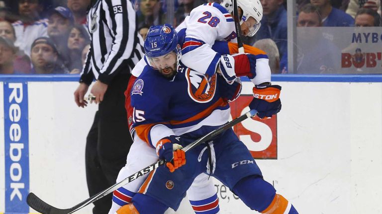 Cal Clutterbuck of the New York Islanders battles for the puck in the second period against Dominic Moore of the New York Rangers at Nassau Coliseum on Tuesday, March 10, 2015.