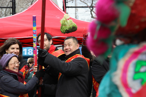 Julie Menin, at rear left, got into the mix at Chinese Lunar New Year festivities at S.D.R. Park as a nearby lion dancer readied to make a play for a head of lucky lettuce. Joining her in the fun were, from left, Councilmember Margaret Chin, State Senator Dan Squadron and former City Comptroller John Liu.  Photo by Milo Hess