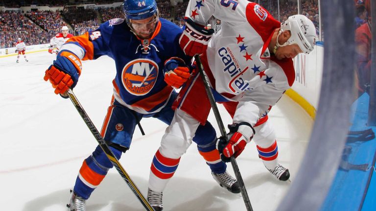 Jason Chimera #25 of the Washington Capitals is checked by Calvin de Haan #44 of the New York Islanders during the first period in Game 3 of the Eastern Conference quarterfinals during the 2015 NHL Stanley Cup playoffs at the Nassau Veterans Memorial Coliseum on April 19, 2015.