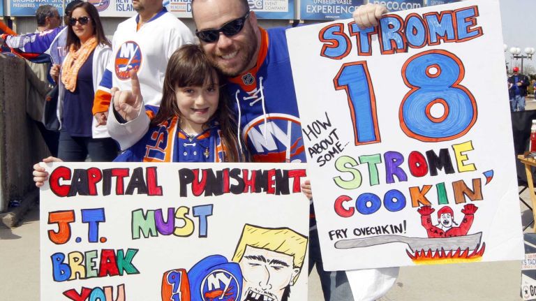 Robert and Sarah Anderson, of Lynbrook, hold up their signs before Game 3 of the Eastern Conference quarterfinals between the New York Islanders and the Washington Capitals at Nassau Coliseum on Sunday, April 19, 2015.