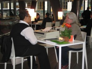 Poet Kamilah Aisha Moon  chats with a woman before creating a poem for her at the Fulton Center. Downtown Express photo by Dusica Sue Malesevic