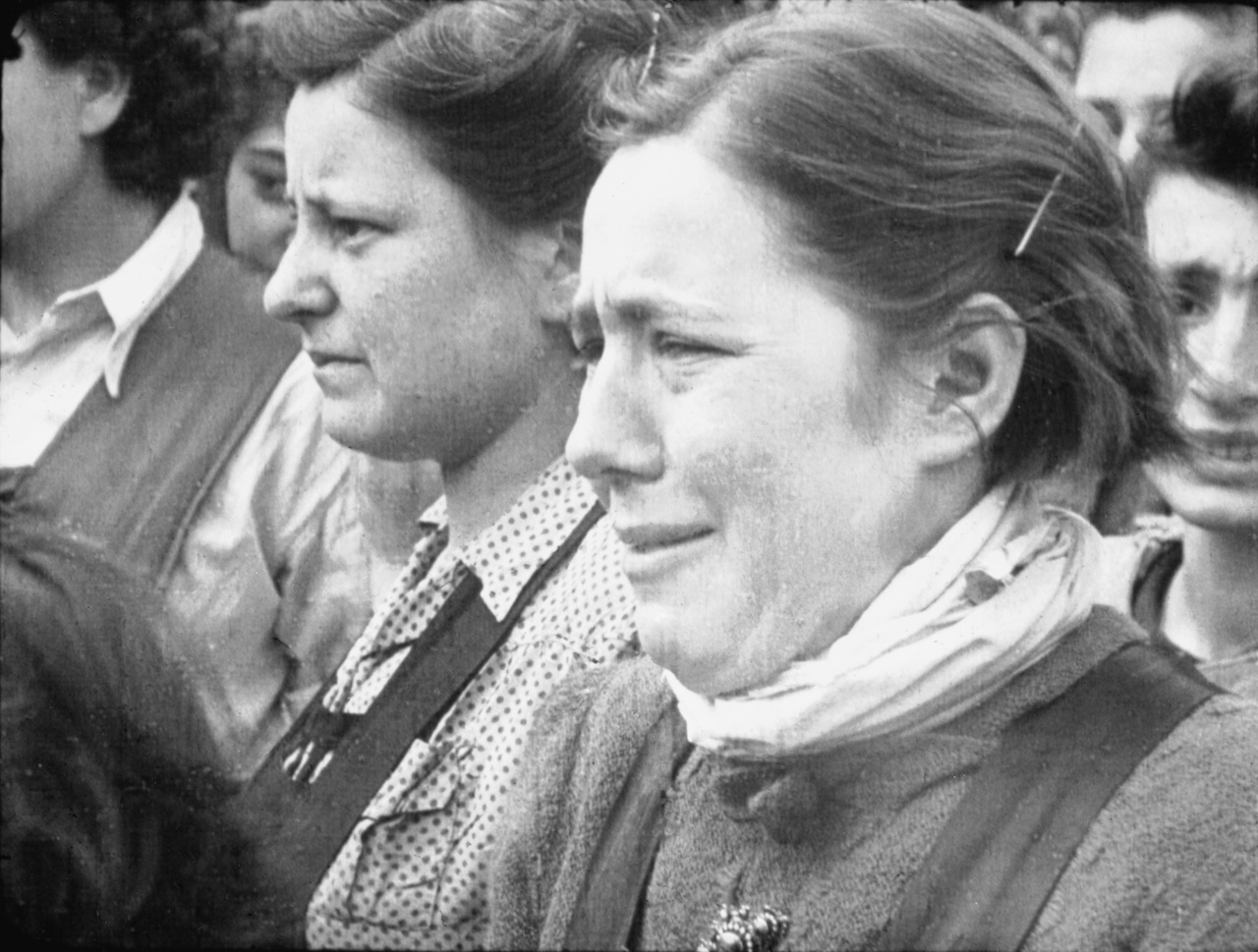 Captioned "Reaction of a Girl," a distressed young woman watches a burial at Bergen-Belsen. From footage shot by Sergeant  Lewis, April 17, 1945. 