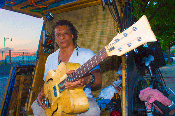 Curbside Homestead, and Hope, for Former Chelsea Merchant 1 Randy Morris lives alongside the West Side Highway within a self-made bicycle trailer, where he crafts handmade guitars. Photo by Zach Williams.