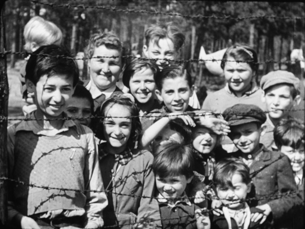 “Smiling children through barbed wire,” a still from footage of Bergen-Belsen shot by Sergeant Lewis or Sergeant Lawrie, April 18-20, 1945. The British liberated the concentration camp on April 15.  Images courtesy Imperial War Museums
