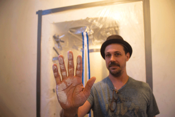 Last August, James Peterson, a tenant at 309 E. Eighth St., showed his hand after wiping it over the construction dust that was then coating his door. The East Village building is owned by Steve Croman. Tenants charge that the landlord was using construction to harass them and force them out of their rent-regulated apartments. File photo by Zach Williams