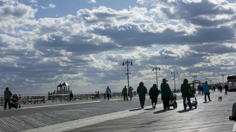 People walk along the boardwalk in Brighton Beach in Brooklyn on April 28, 2015. By Anthony Lanzilote