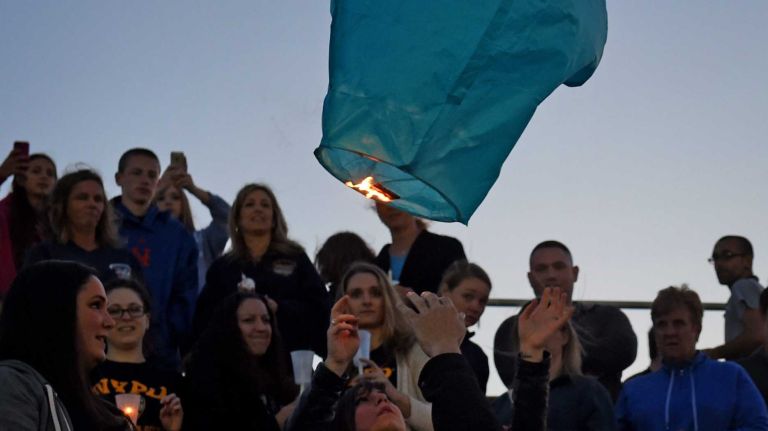 People light a lantern in stands of the football field at Plainedge High School during a memorial service for slain NYPD Police Officer Brian Moore Plainedge High School, his alma mater, on Monday, May 4, 2015. 