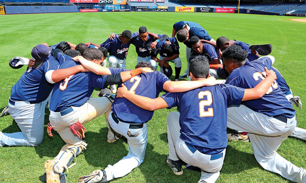 As was their custom, before the championship game, the East Side players knelt in left field for a moment of focus and team togetherness.   Photos by DAMIEN ACEVEDO