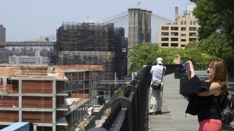 Pedestrians walk and take in the views along the Brooklyn Promenade on June 8, 2015. Brooklyn Heights residents are  concerned that the height of the under construction Pierhouse development, left, in Brooklyn Bridge Park, will block views of the Brooklyn Bridge and parts of Manhattan.