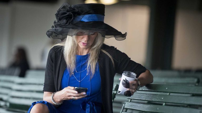Candie Weiss of Thomson, Conn., looks through the program before the race where Triple Crown challenger American Pharoah was looking to make history at Belmont Park Race Track in Elmont Saturday, June 6, 2015.