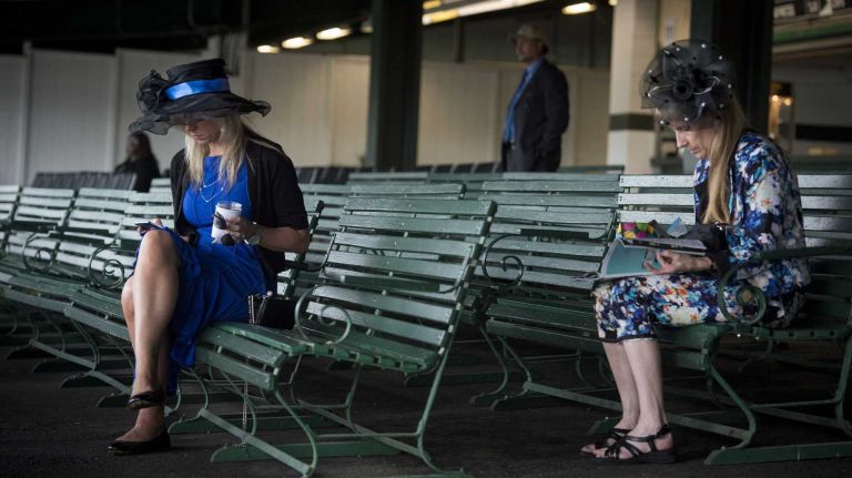 Candie Weiss of Thomson, Conn., and April Bodinizzo of Holden, Mass., check the program hours before the race where Triple Crown challenger American Pharoah sought to make history at Belmont Park Race Track in Elmont Saturday, June 6, 2015.