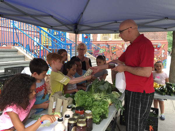 At PS11’s Farm Market, Third Graders In Business While School’s Out 3 Finn, who likes to sell produce, exchanges money with a customer. Photo by Alicia Green.