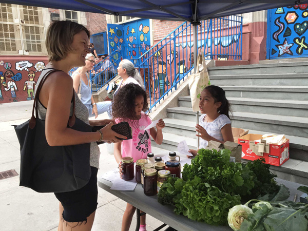 At PS11’s Farm Market, Third Graders In Business While School’s Out 4 A student explains the different items sold at the market to a customer, noting raw honey as one of her favorites. Photo by Alicia Green.