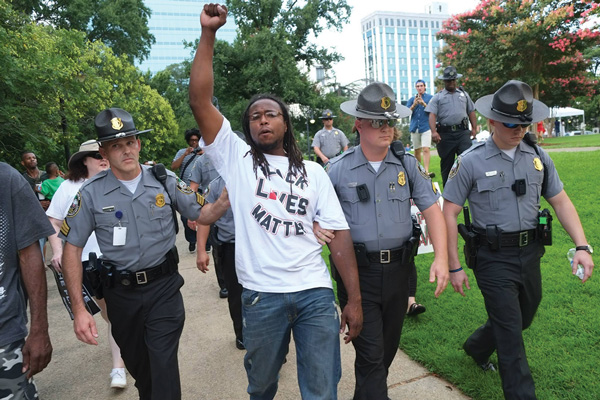 A man is arrested on July 4 for burning a small paper Confederate flag on the grounds of the South Carolina State House.  Photos by John Penley