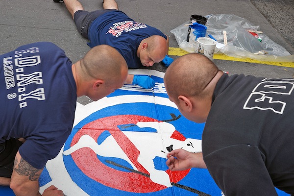 Firefighters painting the new logo outside Ladder 8's Ghostbusters firehouse last Tuesday, June 28. Downtown Express photo by Milo Hess.
