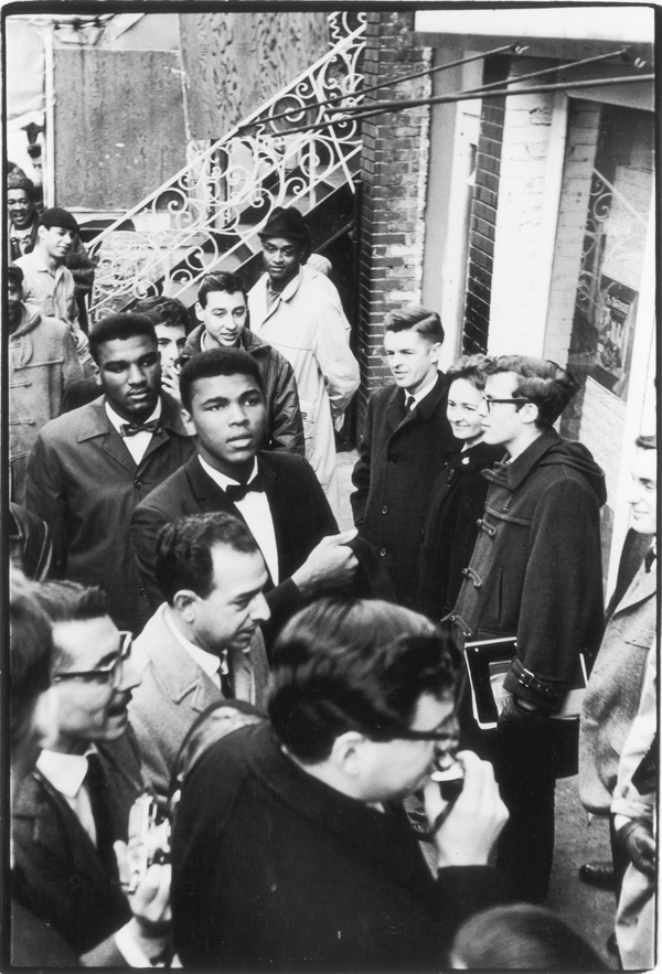 Surrounded by fans and journalists, boxer Muhammad Ali — then still known as Cassius Clay — arrives at The Bitter End club, 147 Bleeker St., where he participated in a poetry reading, on March 12, 1963.   Photo © by Fred W. McDarrah