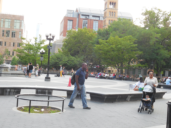 A man on a cell phone walks by another one of the “accident-waiting-to-happen” empty tree pits.