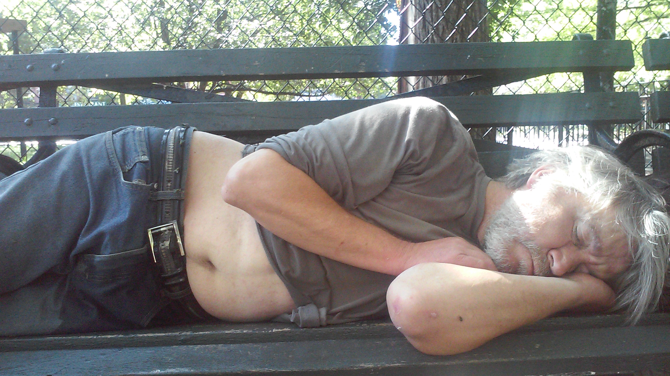 Another man sleeping on a bench in Tompkins Square Park.
