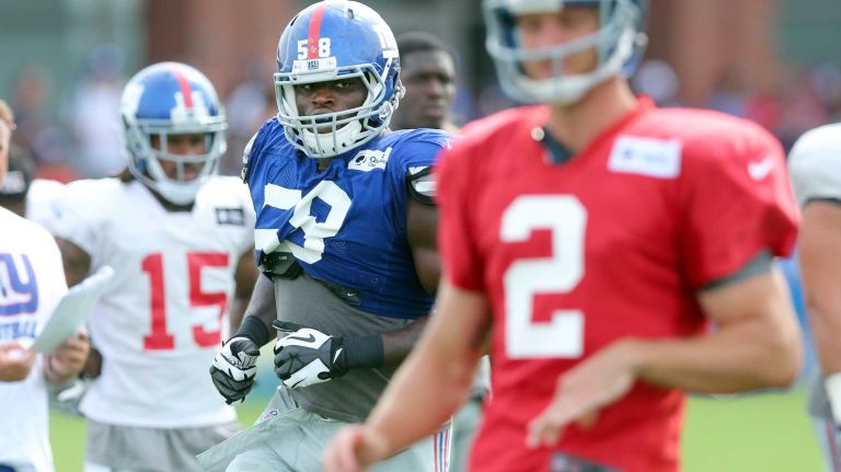 New York Giants defensive end Owamagbe Odighizuwa trails behind quarterback Ricky Stanzi during training camp at the Quest Diagnostics Training Center in East Rutherford, N.J., on Saturday, Aug. 8, 2015.