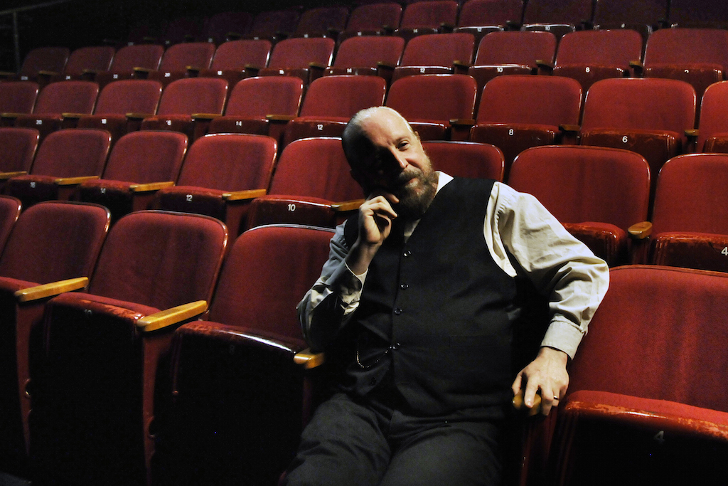 Lorcan Otway sitting in the theater he helped create when, as a child, he helped dig dirt out of the building's basement for the space.