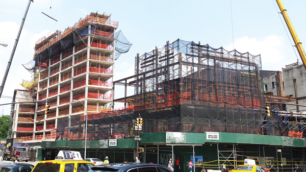 Last July, when this photo was taken, construction was going on simultaneously on two major projects on Sixth Ave. between Spring and Vandam Sts., the God’s Love We Deliver building, at right, and the neighboring new luxury residential building, at left.   File photo by The Villager