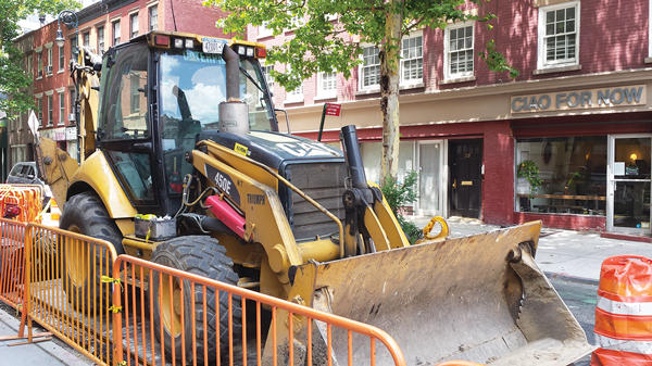 A parked tractor and stacked pipes are still blocking a lane of the street on W. 10th St. between Greenwich and Sixth Aves., and are still negatively impacting businesses along the street.  Photo by Lincoln Anderson