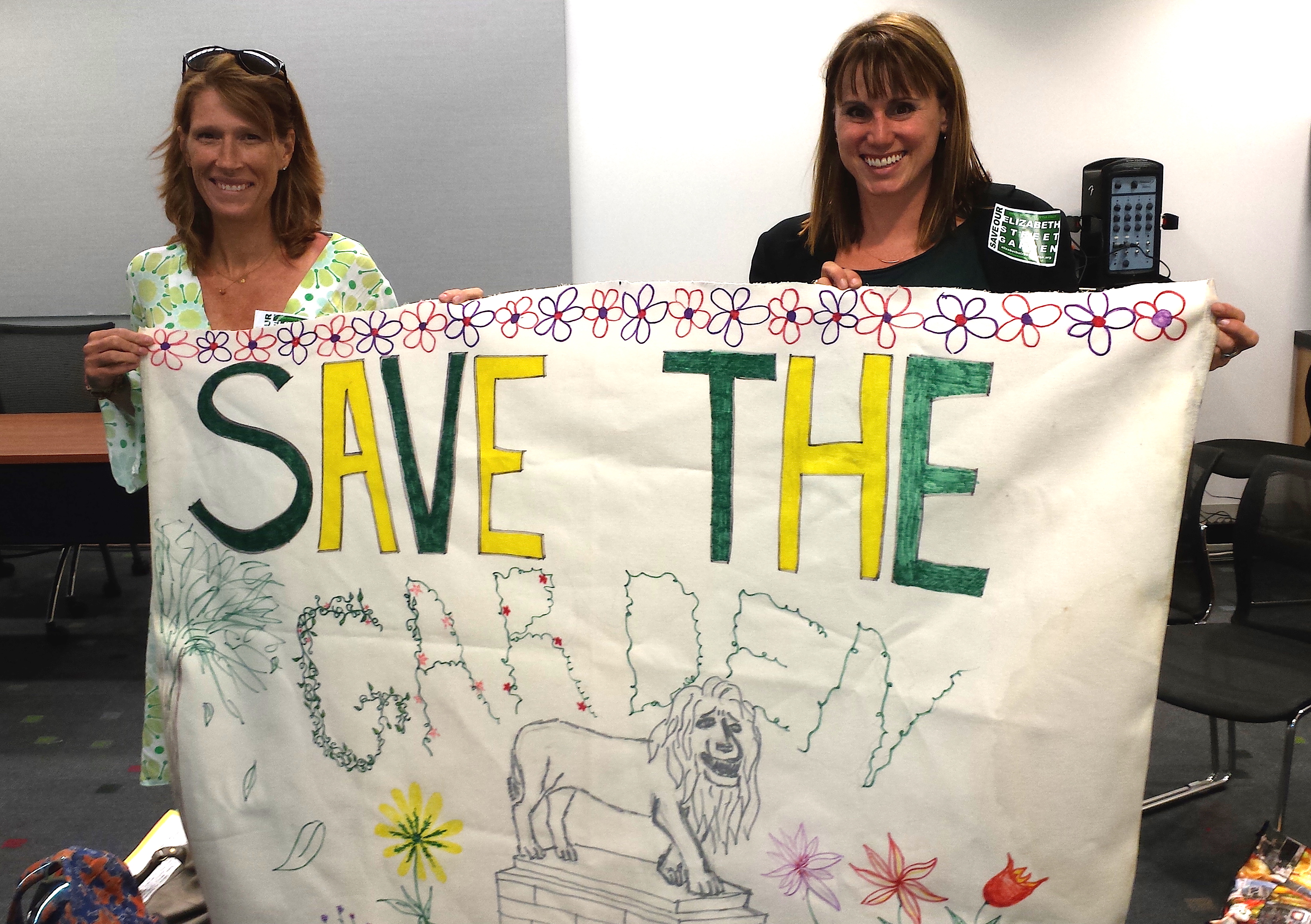 Elizabeth St. Garden leaders Emily Hellstrom, left, and Jeannine Kiely proudly displayed a banner for the garden at a hearing last year for funding from the Lower Manhattan Development Corporation for an affordable housing project proposed for the garden. L.M.D.C. denied the funds, but the city and City Councilmember Margaret Chin are still pushing on with the face in the face of united community and political opposition.