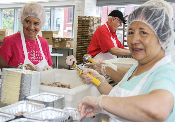 Volunteers putting scoops of cranberry scone dough in individual tins.