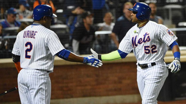 New York Mets second baseman Juan Uribe congratulates leftfielder Yoenis Cespedes on his solo home run against the Miami Marlins during the third inning of a game at Citi Field on Monday, Sept. 14, 2015.