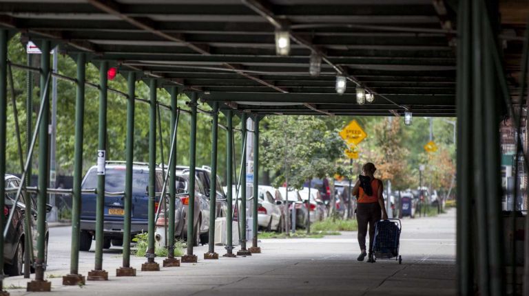 A woman walks under a sidewalk shed in front of 409 Edgecombe Ave. in Manhattan on Friday, Sept. 11, 2015. There are more than 7,000 of the unsightly sheds covering the city's streets, which has drawn the attentions of watchdogs and officials. 