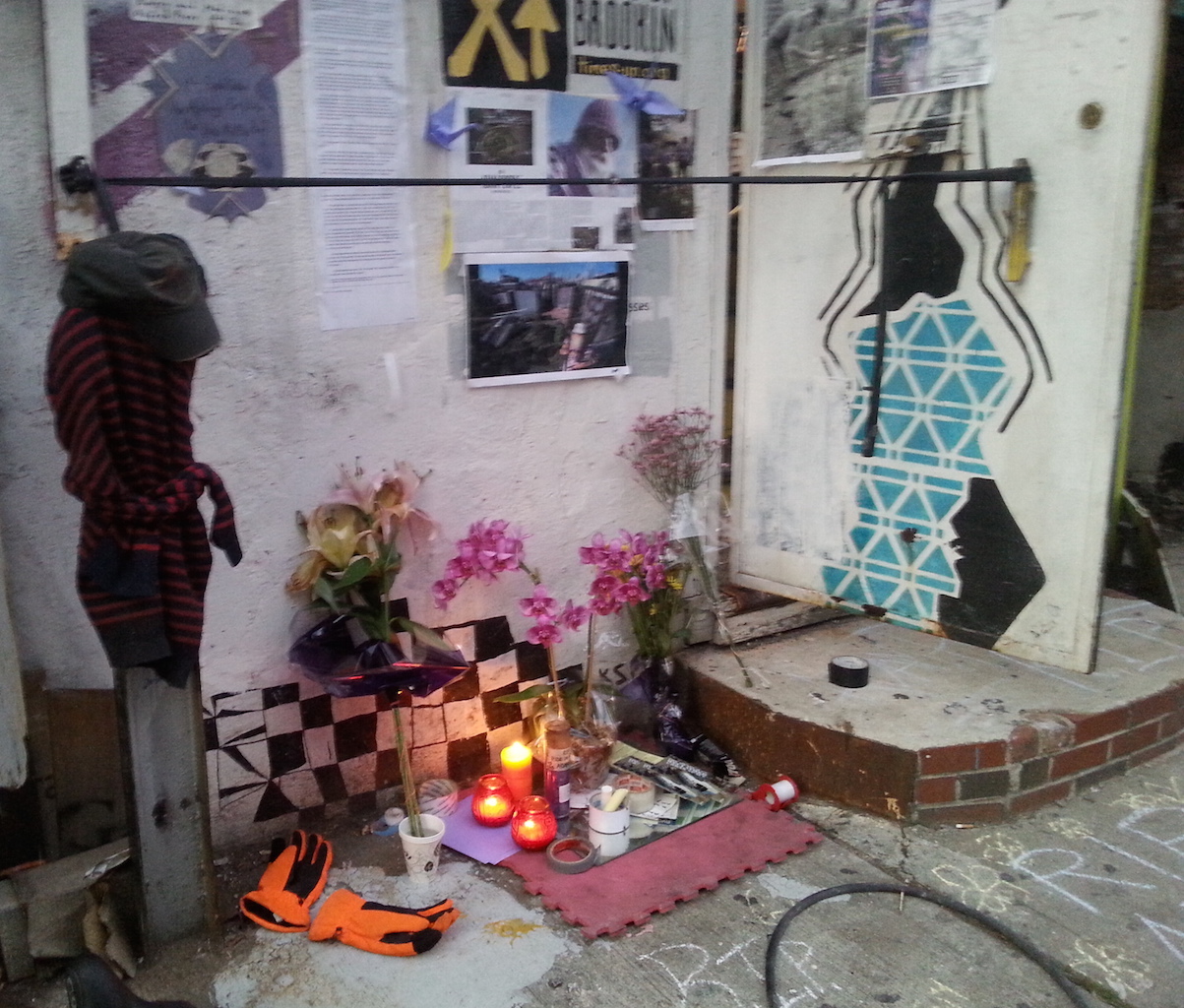 A memorial to Adam Purple — including purple flowers and his orange winter gloves — is growing at the Time's Up space in South Williamsburg.