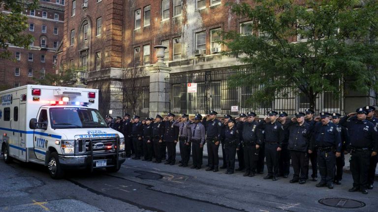 Officers salute as the remains of NYPD police officer Randolph Holder pass by in an ambulance as they leave the New York Medical Examiner's office in Manhattan on Wednesday, Oct. 21, 2015. Officer Holder was shot and killed in the line of duty trying to apprehend a robbery suspect in East Harlem.