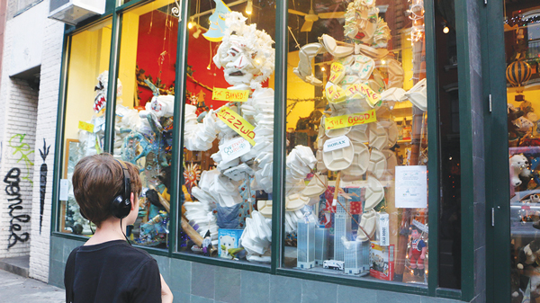 A student from East Village Community School looking at the giant Styrofoam puppets in the Dinosaur Hill toy store window on E. Ninth St., their permanent home.   Photo by Atsuko Quirk