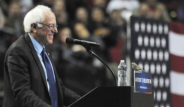 Coal mine canary perched on NY Primary 1 Democratic presidential candidate Sen. Bernie Sanders smiles as a bird lands on his podium as he speaks during a rally at the Moda Center in Portland, Ore., on Mar. 25 (robot bird provided by ultra-secret Socialist Super PAC). AP photo by Steve Dykes.