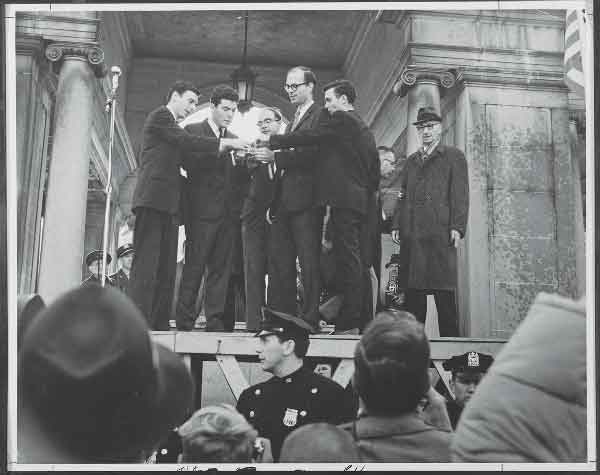 Photo by Neil Haworth, courtesy of War Resisters League Draft-card burners in 1965 at the Union Square Pavilion, from left, Tom Cornell, Marc Edelman, Roy Lisker, David McReynolds and Jim Wilson. Dutch-born clergyman and activist A.J. Muste is at right in hat and topcoat.