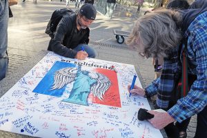Photo by Milo Hess Supporters express solidarity with the people of Paris by signing posters adorned with an angelic image of the Statue of Liberty, a gift from France that was a potent symbol of strength for New Yorkers after the 9/11 attacks.