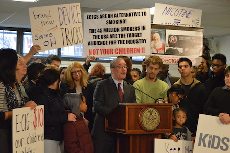 Manhattan Pols, Anti-Smoking Groups Decry E-Cigarette Marketing Toward Youth 1 Even as elected officials including City Comptroller Scott Stringer (at podium) and Assemblymember Linda Rosenthal (to the left of Stringer facing the photo) denounced vaping marketing target youth, e-cigarette advocates managed to get their perspective into the picture. | JACKSON CHEN