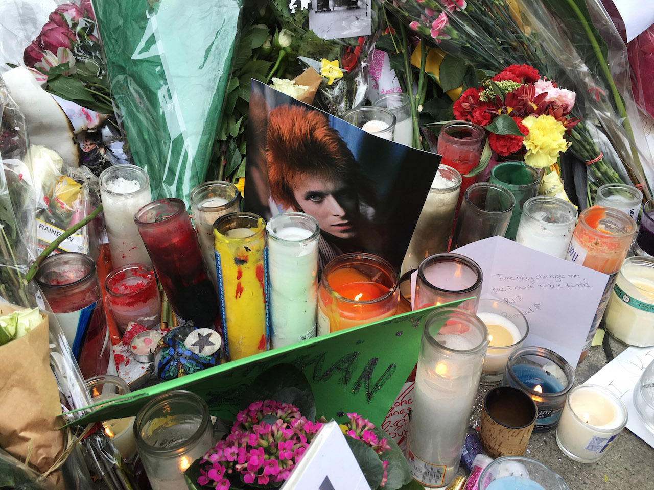 A photo of David Bowie during his Ziggy Stardust period amid votive candles and flowers at the memorial in front of his Soho building.  Photo by Q. Sakamaki 