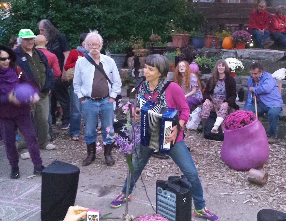 Fran Luck, far left, bobbling purple dodge ball, at Adam Purple's memorial, at La Plaza Cultural, on Sept. 24, listening to a woman perform a song about her memories of the famous gardener. To the right of Luck are environmental attorney Joel Kupferman and Yippie pot-legalization advocate Dana Beal. At the time of the memorial, the story of Adam Purple's history of child sexual abuse had not yet been broken by The Villager. File photo by The Villager