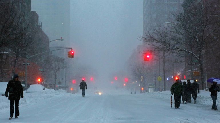 Pedestrians walk through the snowy streets of the Upper East Side as all cars but emergency vehicles are banned from driving on the road on Jan. 23, 2016 in New York City.